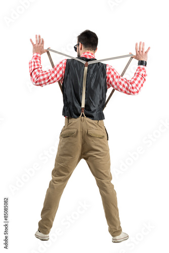 Back view of hipster man holding and stretching suspenders