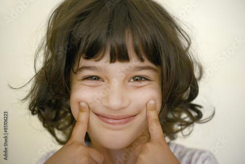 Niña estirándose los labios para mostrar sonrisa