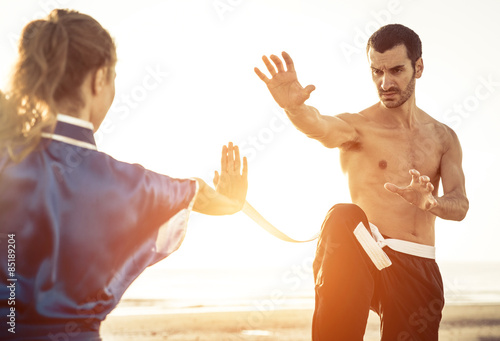 couple training martial arts on the beach
