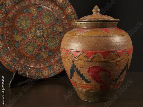 Decorative ceramic vessel beside an engraved dish