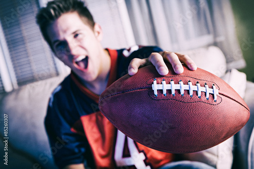 Football: Man Cheering For Team On TV And Holding Out Ball