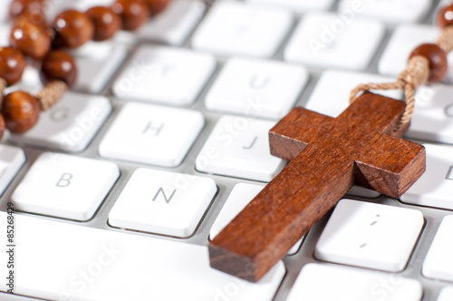 Brown christian cross necklace on white modern computer keyboard