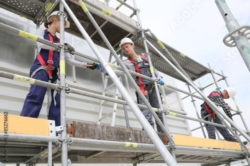 Construction workers installing scaffolding on site