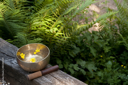 tibetan bowl made of seven metals with water and yellow flowers