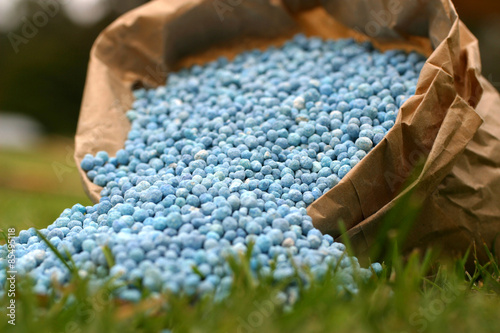 Blue fertiliser in brown bag on green grass