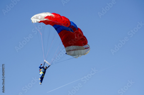 Skydiver in blue suite paragliding on a red white blue parachute