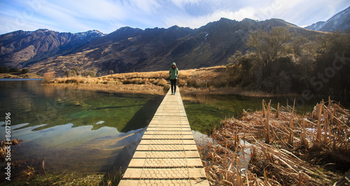 Young adult woman standing alone on the bridge at Moke Lake, Que