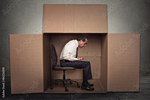 Man sitting in a box working on laptop computer