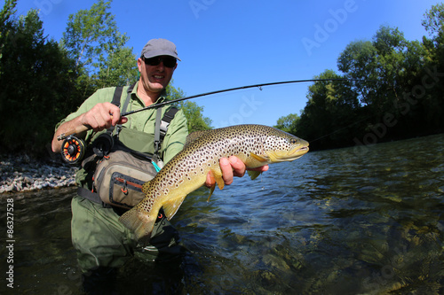 Fisherman holding recently caught brown truit