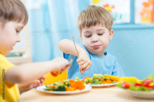 kids children eating vegetables in kindergarten or at home