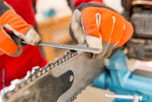 Sharpening a chainsaw Close up on a man sharpening a chainsaw chain with file.