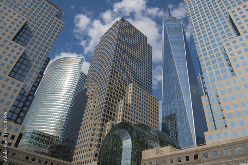 Downtown Manhattan skyline featuring modern shiny skyscrapers under bright blue sky