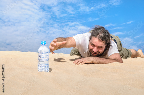 Thirsty man in the desert reaches for a bottle of water