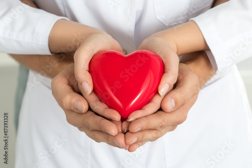 Woman's and man's hands holding red heart together