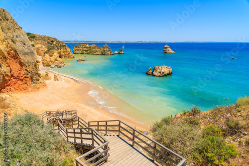 Wooden walkway to famous Praia Dona Ana beach with turquoise sea water and cliffs, Portugal