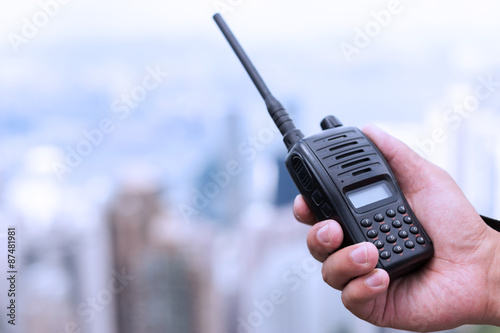 hand holding walky talky with cityscape as background