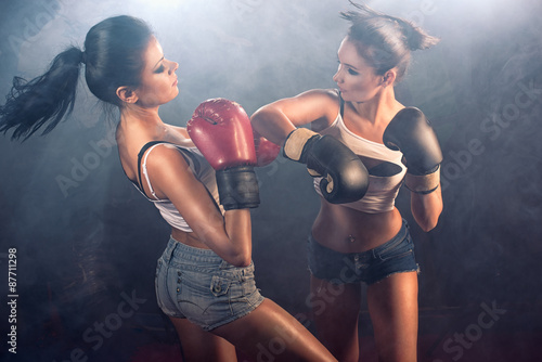 Two attractive athletic girls sparring at gym