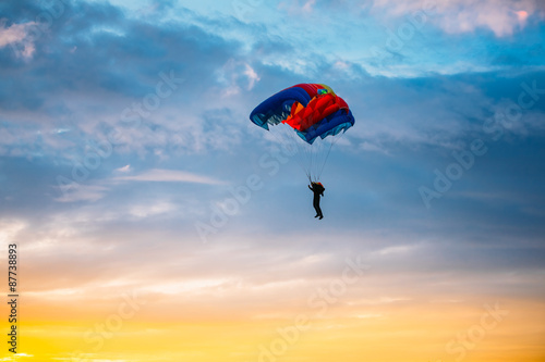 Skydiver On Colorful Parachute In Sunny Sky