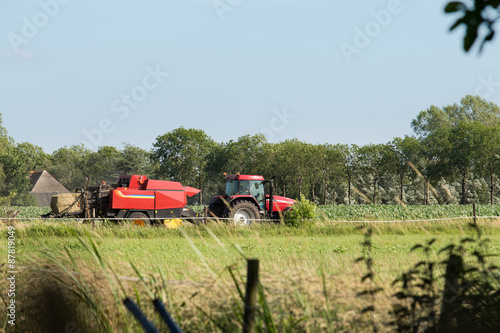 Gedroogd gras wordt door een loonbedrijf in balen geperst in een weiland in Zwolle, Overijssel Nederland