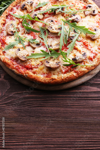 Tasty pizza with vegetables and arugula on wooden background
