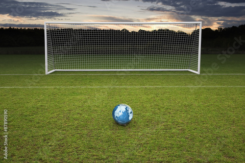 empty amateur football goal posts and a leather football with globe map on ball