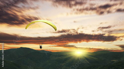 Paragliding at sunset with purple clouds