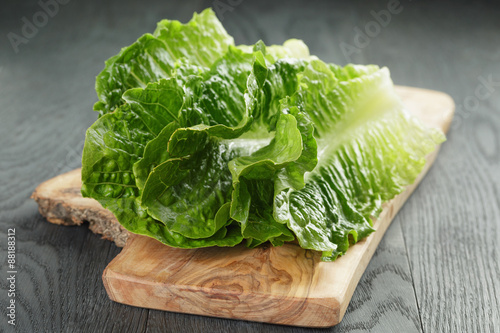 fresh romain green salad leaves on olive board