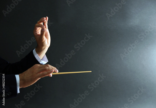 Music conductor hands with baton on black background