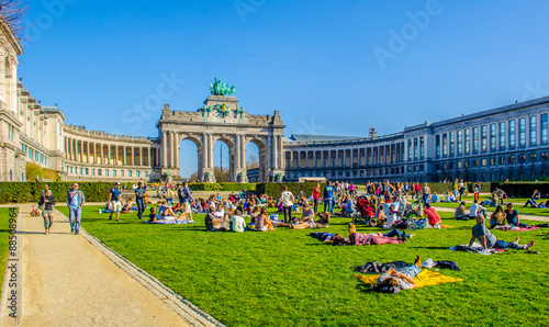 People are relaxing next to cinquantenaire monument in brussels during first sunny weekend in March.