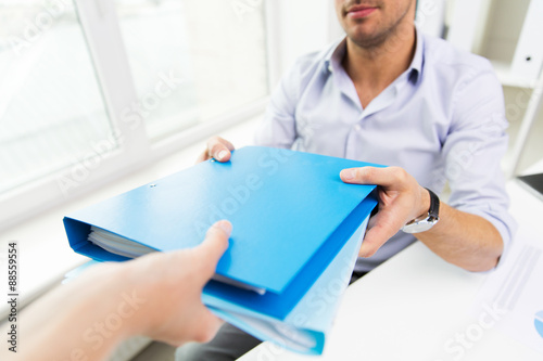 close up of businessman taking folders from hand