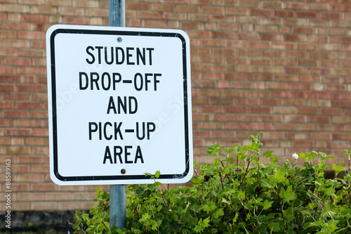 Sign for Student Drop off and Pick Up Area against brick school building