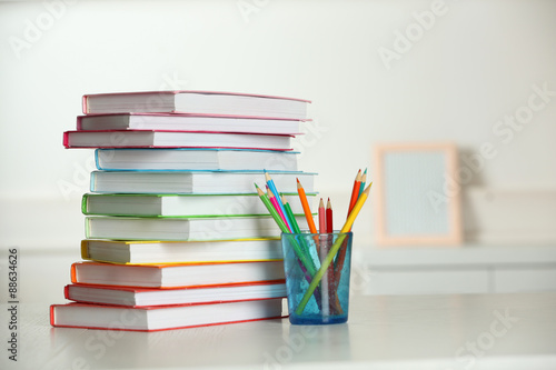 Colorful books and pencil on table in room