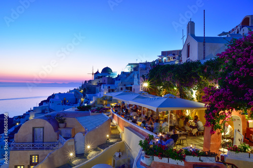 Dusk scene on the seaside with public terrace in evening lights in Oia Santorini, Greece