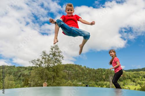 Children bouncing up and down on trampoline