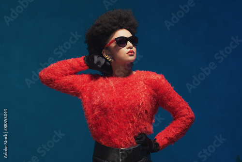 Woman poses in fashionable attire with sunglasses