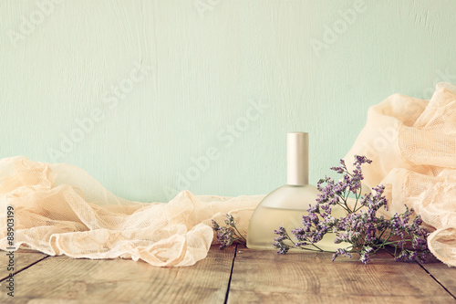 vintage perfume next to flowers on wooden table. retro filtered image 