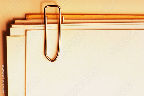 view of a paper clip with stack of blank paper