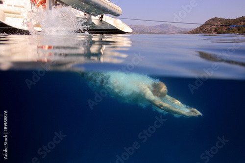 underwater view of young girl taking a header into crystal clear open ocean water