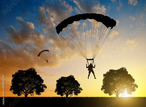 Silhouette skydiver parachutist landing at sunset