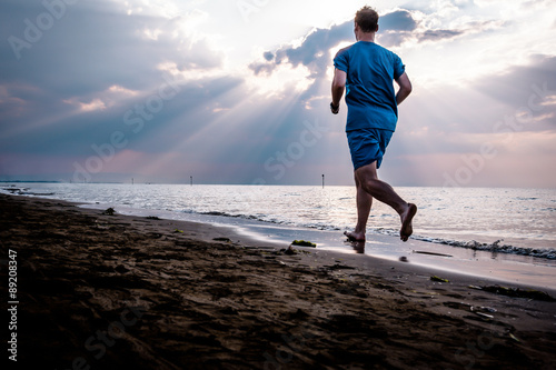 Uomo che corre sulla spiaggia all'alba