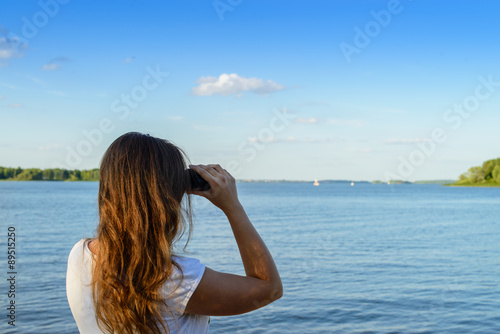 Woman looking through binoculars as a for a bright future, lands