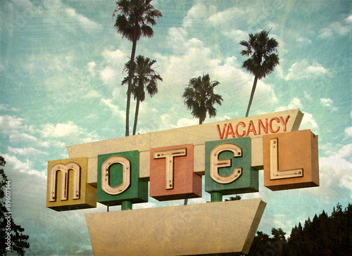 ged and worn vintage photo of retro motel sign with palm trees