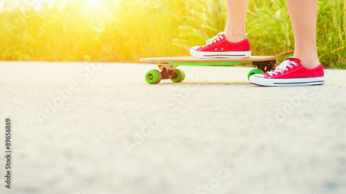 Anonymous teenage girl with skateboard, image with sunflare