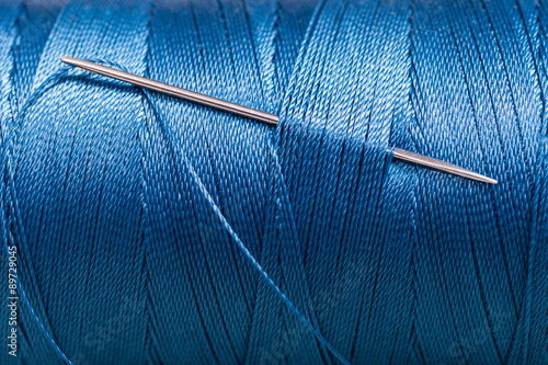 sewing needle in blue thread bobbin