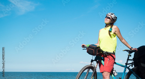 Woman with bicycle joyng sun on seaside and smiling
