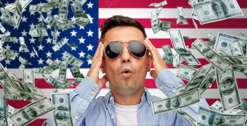 surprised man under money rain over american flag