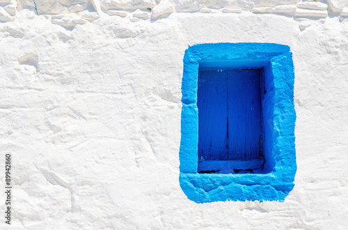 Blue wooden window on white stone wall, Greece