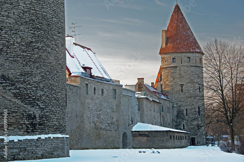 Tallin old city wall and tower in the winter snow and under a storm laden sky.