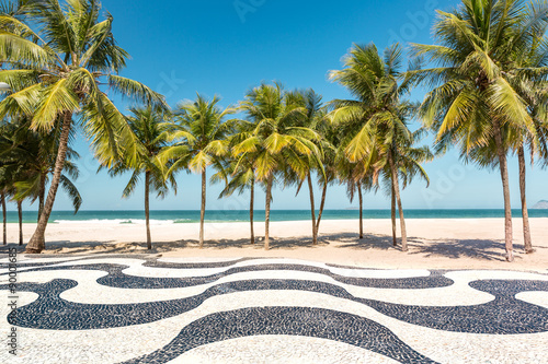 Palm trees and the iconic Copacabana beach mosaic sidewalk, in Rio de Janeiro, Brazil.
