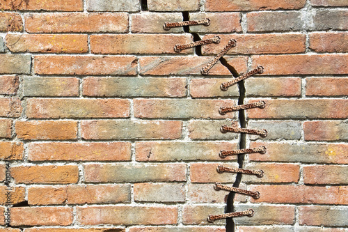 Cracked brick wall with with a metal seam - concept image